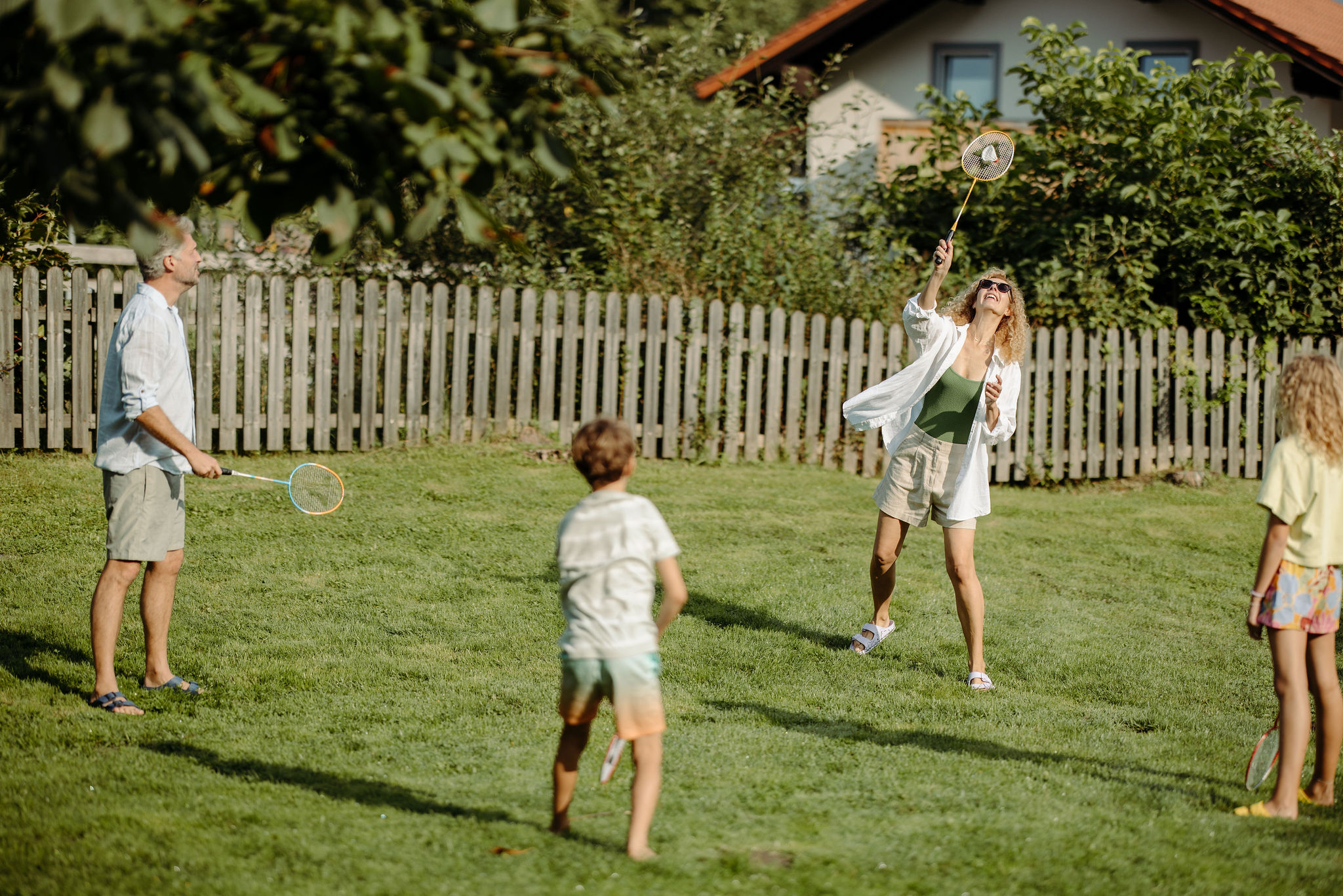 Familie spielt Federball im Garten an einem sonnigen Tag