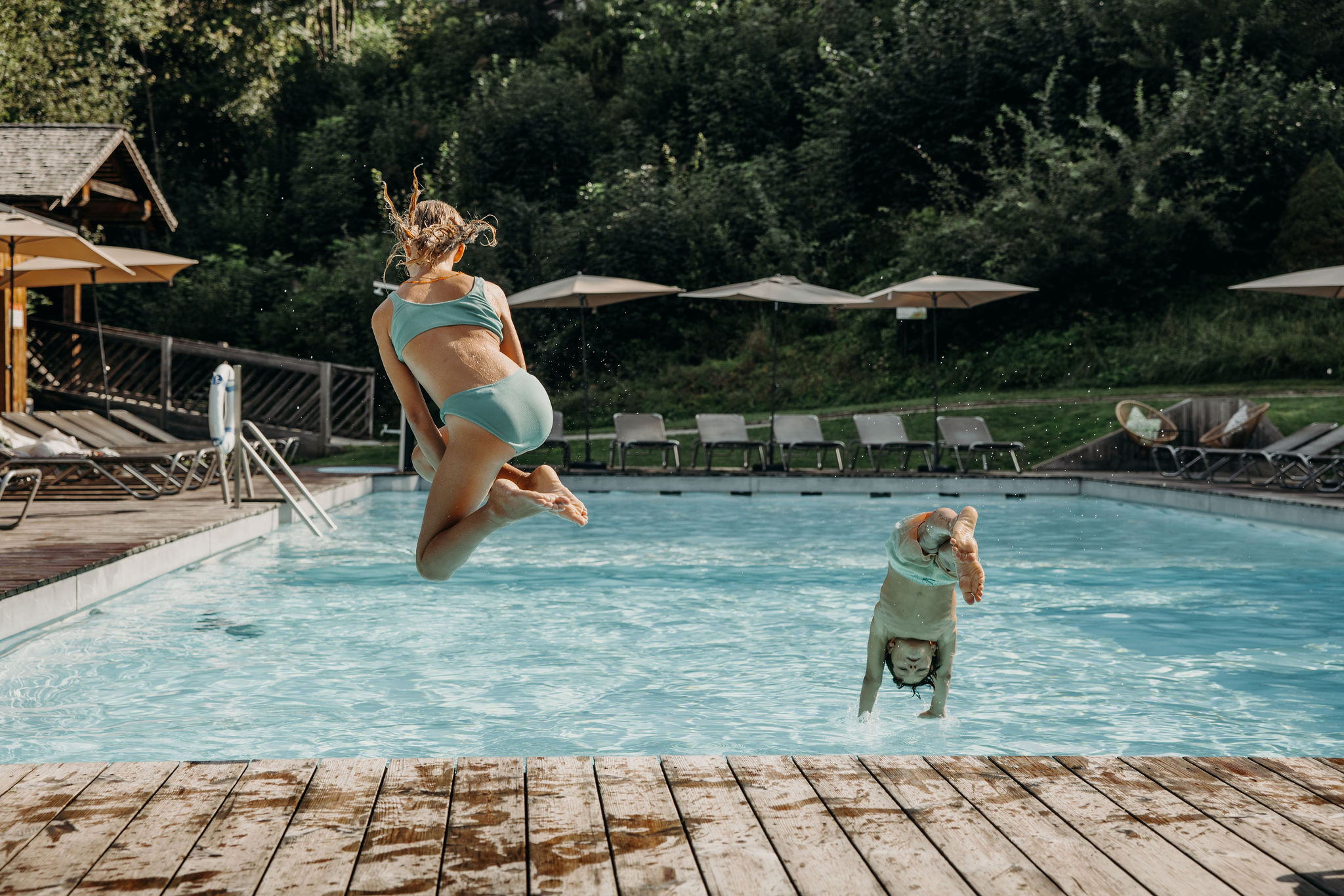 Zwei Kinder springen in den Resl Pool im Sommer