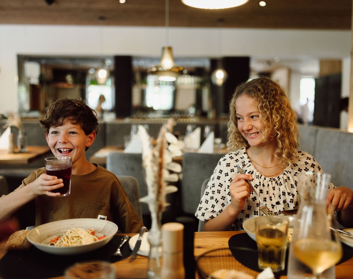 Zwei Kinder essen lächelnd in einem Restaurant